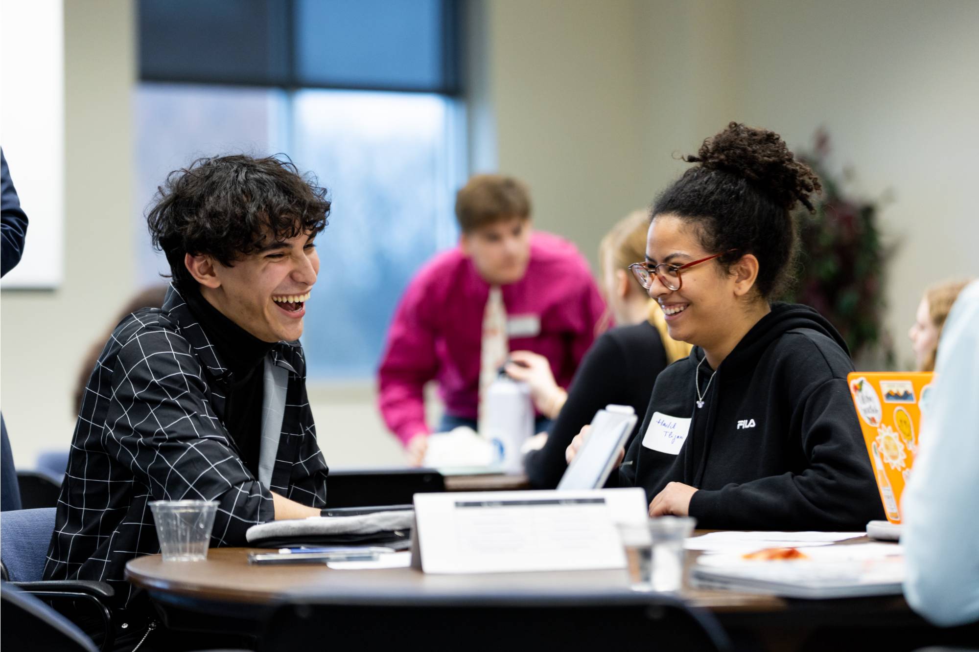 Students sitting at a table and laughing at an Elect Her event